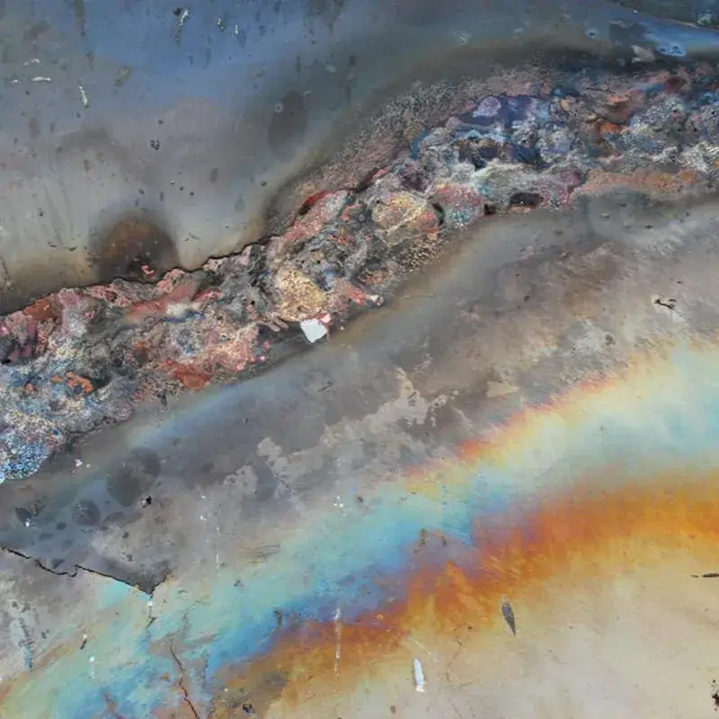 Severe dark rainbow heat tint and thermal distortion on stainless steel caused by TIG welding.